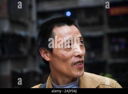 (200106) - chongqing, Januar 6, 2020 (Xinhua) - Lief Guanghui wartet auf Kunden in der Nähe von einem Einkaufszentrum an der Chaotianmen im Südwesten Chinas Chongqing Gemeinde, Jan. 5, 2020. Lief Guanghui, 50, hat sein Leben als 'Bang Bang', buchstäblich 'Tick', in Chongqing seit zehn Jahren erwarb. In einer bergigen Stadt Chongqing mit einer Fülle von hügeligen Straßen und Wege, stick Männer haben unterstützt Menschen, die von Gepäck und schwere Sachen. Schleppen waren auf Bambusstangen auf ihren Schultern ausgeglichen, der Stick Männer verdienten Brot im Schweiße Ihrer Augenbrauen. Wurde lief einer von ihnen im Jahr 2009 als er lef Stockfoto