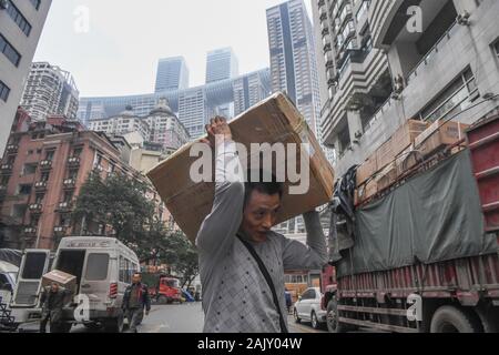 (200106) - chongqing, Januar 6, 2020 (Xinhua) - Lief Guanghui trägt Waren an Chaotianmen im Südwesten Chinas Chongqing Gemeinde, Jan. 5, 2020. Lief Guanghui, 50, hat sein Leben als 'Bang Bang', buchstäblich 'Tick', in Chongqing seit zehn Jahren erwarb. In einer bergigen Stadt Chongqing mit einer Fülle von hügeligen Straßen und Wege, stick Männer haben unterstützt Menschen, die von Gepäck und schwere Sachen. Schleppen waren auf Bambusstangen auf ihren Schultern ausgeglichen, der Stick Männer verdienten Brot im Schweiße Ihrer Augenbrauen. Ran wurde einer von ihnen im Jahr 2009 als er verließ seine Heimatstadt Dianjiang, Stockfoto