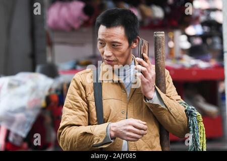 (200106) - chongqing, Januar 6, 2020 (Xinhua) - Lief Guanghui beantwortet einen Anruf von einem Kunden im Südwesten Chinas Chongqing Gemeinde, Jan. 5, 2020. Lief Guanghui, 50, hat sein Leben als 'Bang Bang', buchstäblich 'Tick', in Chongqing seit zehn Jahren erwarb. In einer bergigen Stadt Chongqing mit einer Fülle von hügeligen Straßen und Wege, stick Männer haben unterstützt Menschen, die von Gepäck und schwere Sachen. Schleppen waren auf Bambusstangen auf ihren Schultern ausgeglichen, der Stick Männer verdienten Brot im Schweiße Ihrer Augenbrauen. Ran wurde einer von ihnen im Jahr 2009 als er verließ seine Heimatstadt Dianjiang Stockfoto