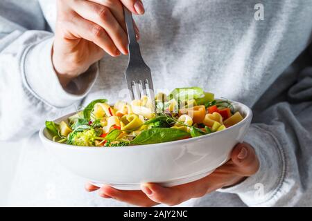 Valentinstag essen Konzept. Frau Salat mit Pasta Herz, Oliven, Tomaten, Spinat und Brokkoli. Stockfoto