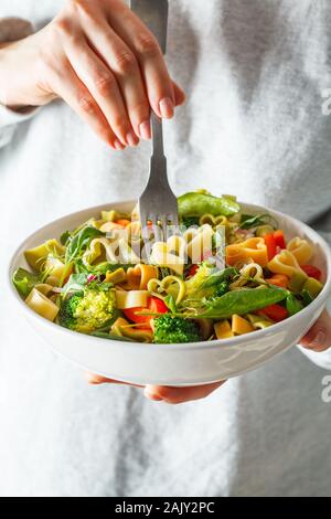 Valentinstag essen Konzept. Frau Salat mit Pasta Herz, Oliven, Tomaten, Spinat und Brokkoli. Stockfoto