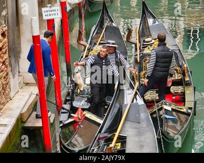 Ein gondoliere bereitet ein Kunde an Bord als nähert er Gondeln auf einen kleinen Kanal in Venedig, Italien, günstig zu helfen. Stockfoto