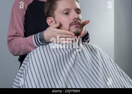 Nahaufnahme der Haarschnitt und Bart. Eine professionelle Master bereitet einen Kunden Bart zum Schneiden und Rasieren ein Bart. Macht Bart Massage, Haar s Stockfoto