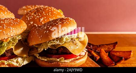 Burger auf einem Holzbrett mit Kartoffeln. Lecker Foto fast food. Für Text platzieren. Stockfoto