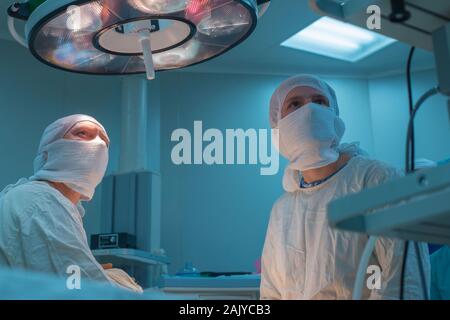 Der Chirurg und sein Assistent im Operationssaal Blick auf den Monitor, die Durchführung einer laparoskopischen Operation. Behandlung der Inguinalen Hernien in childre Stockfoto