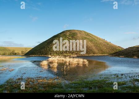 Der riesige neolithische Kreidehügel von Silbury Hill, Avebury, Wiltshire, Großbritannien, spiegelte sich in einer überfluteten Wiese wider. Er ist 40 m hoch und wurde um 2300 v. Chr. erbaut Stockfoto