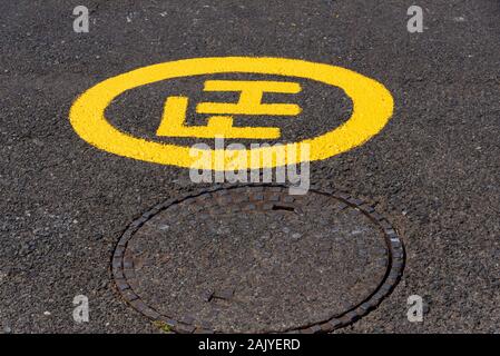 Südafrika. Dezember 2019. Eine frisch gestrichene Hydrant gelbes Schild neben einem Kanaldeckel. Stockfoto