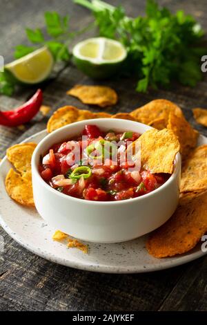 Leckere mexikanische nachos Chips in der Schüssel mit Salsa dip auf hölzernen Tisch. Stockfoto