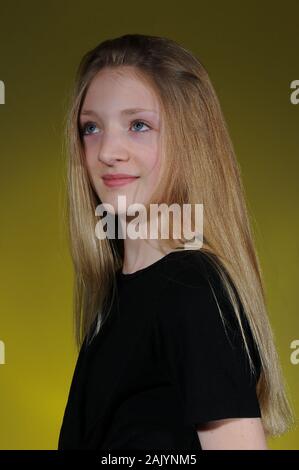 Hübsche blonde Kaukasischen Jugendmädchen in einem schwarzen T-Shirt auf einem hellen abgestuften Hintergrund isoliert Stockfoto