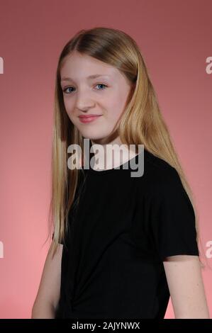 Hübsche blonde Kaukasischen Jugendmädchen in einem schwarzen T-Shirt auf einem hellen abgestuften Hintergrund isoliert Stockfoto