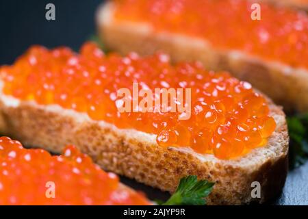 Sandwiches mit rotem Kaviar auf dunklem Stein Hintergrund Stockfoto