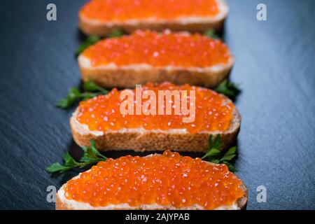 Sandwiches mit rotem Kaviar auf dunklem Stein Hintergrund Stockfoto