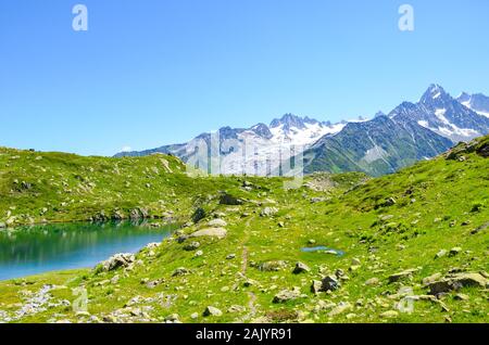 Alpine Lac de Cheserys Cheserys, See in der Nähe von Chamonix-Mont-Blanc in den Französischen Alpen. Glacier Lake mit hohen Bergen im Hintergrund. Tour du Mont Blanc Trail. Grüne alpine Landschaft. Stockfoto