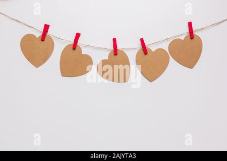 Foto von fünf Papier Herzen hängen an einem Seil mit roten Wäscheklammern auf weißem Hintergrund Stockfoto