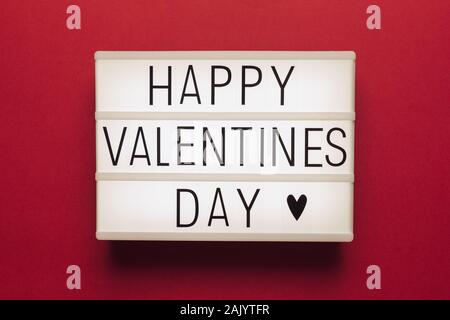 Foto eines weißen Licht, mit rotem Hintergrund und schwarzer Schrift mit dem Text 'Happy Valentines Day" Stockfoto