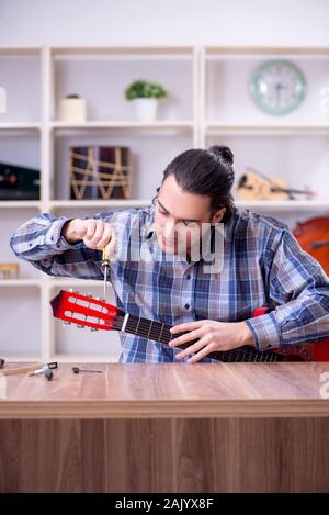 Die junge schöne Handwerker Reparatur Gitarre Stockfoto