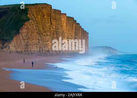 West Bay, Dorset, Großbritannien. 6. Januar 2020. UK Wetter. Raue See crash an Land am East Beach an der West Bay in Dorset wie das Licht verschwindet in der Abenddämmerung mit Blick auf den berühmten Klippen, die in der ITV-Broadchurch empfohlene. Foto: Graham Jagd-/Alamy leben Nachrichten Stockfoto