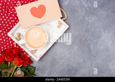 Valentinstag Konzept. Kaffee am Morgen, Umschlag mit roten Herzen, Rosen auf Grau. Freien Speicherplatz. Platz für Text. Stockfoto