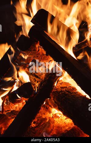 Feuer - orangenes Feuer Flammen im Kamin, brennende Holzstämme in der Nacht, dunkler Hintergrund Stockfoto