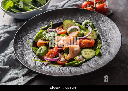 Lachs Salat mit Gemüse in der Platte auf dunklen Küche Tabelle Stockfoto