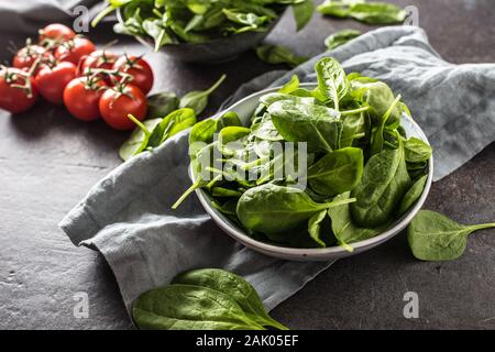 Frische Baby Spinat in der Schüssel auf dunklen Küche Tabelle Stockfoto