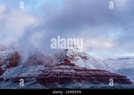 Herrliche Winterlandschaft von Sedona Berge mit Schnee mit Morgennebel und Nebel steigt aus den roten Felsen bedeckt. Stockfoto