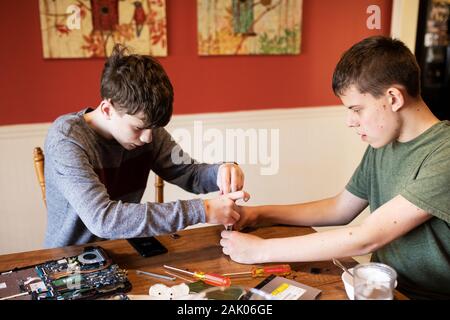 Zwei Jungen im Teenageralter, neben einem alten Laptop Computer. Stockfoto