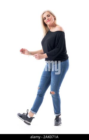 Feminine Mittelalter moderne Frau tanzen sorglos in legere Kleidung tragen Jeans und Turnschuhe. Voller Körper Länge auf weißem Hintergrund. Stockfoto