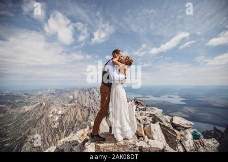 Frisch verheiratetes Paar hat ersten Kuss während der Hochzeit auf Berggipfel, Wyoming. Stockfoto