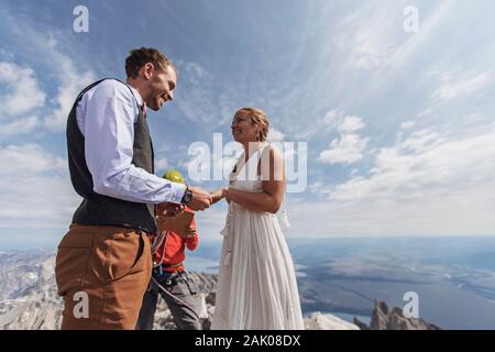 Paare tauschen Gelübde und Ringe während der Hochzeit auf dem Gipfel des Berges Stockfoto