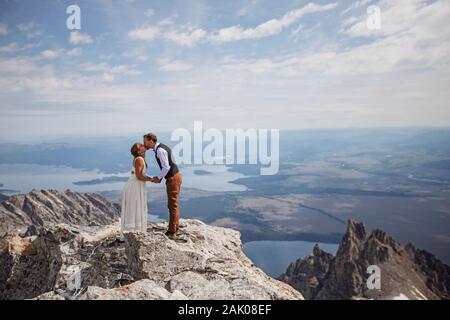 Braut und Bräutigam teilen sich einen Kuss auf dem Gipfel des Berges in Wyoming Stockfoto