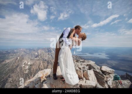 Bräutigam taucht Braut nach dem Heiraten auf dem Gipfel des Berges Stockfoto