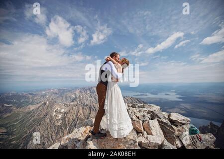 Gerade verheiratetes Paar teilt ersten Kuss auf dem Gipfel des Grand Teton Wyoming Stockfoto