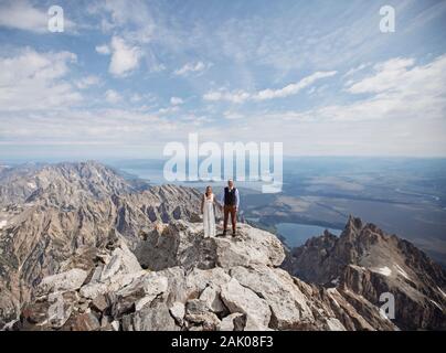 Braut und Bräutigam stehen auf dem Gipfel des Grand Teton, nachdem sie geheiratet haben. Stockfoto