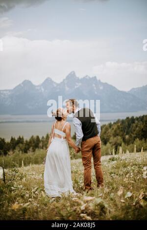 Braut und Bräutigam küssen sich in der Natur vor den Bergen, Wyoming Stockfoto