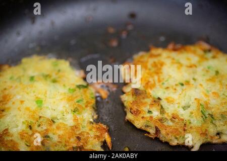Nahaufnahme von zwei Latkes, die in der Pfanne zur Vorbereitung auf Chanukka braten Stockfoto