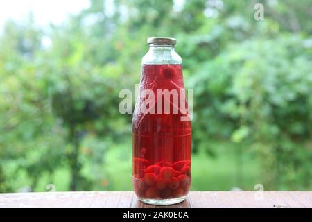 Hausgemachte Glas geschnitten, eingemachte Carneol cherry auf grünem Hintergrund. Carneol cherry "Kompott" entfernt, eine süße Getränke mit gekochten Früchten in grüner Hintergrund Stockfoto