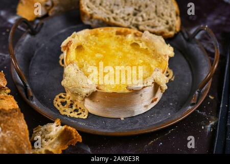 Ofen gebacken und geschmolzenem Käse in runden Holz- Fach mit frischem Brot Schichten verwendet in Käse dip Stockfoto