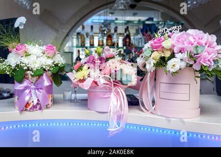 Schönen Blumenschmuck mit Rosen in Luxus Boxen eingerichtet rosafarbenen Bändern auf einer Leiste platziert sind. Stockfoto