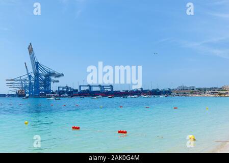 Eine tolle Aussicht auf eine industrielle Hafen mit vielen Frachtschiffe in der Nähe von baukräne auf dem Meer vor dem Hintergrund eines blauen Himmels in Malta. Stockfoto