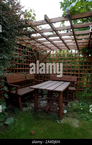 Gartenlaube, geschützt durch azurblaue Wände mit einem Tisch und Bänken Stockfoto