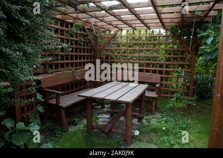Gartenlaube, geschützt durch azurblaue Wände mit einem Tisch und Bänken Stockfoto