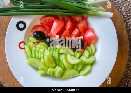 Salat mit frischem Gemüse, Gurken, Tomaten und schwarzen Oliven in einer Platte zum Würzen bereit, Zutaten für eine gesunde Ernährung Stockfoto