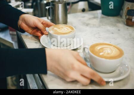 Der Barista oder Verkäufer gibt frisch gebrühten Kaffee an den Besucher. Stockfoto