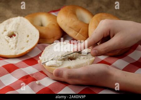 Ein studio Foto der Ausbreitung von Frischkäse auf einer offenen plain Bagel. Stockfoto