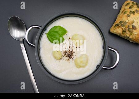 Blumenkohl Suppe im Topf mit Bun auf schwarzem Hintergrund. Ansicht von oben Stockfoto