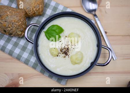 Blumenkohl Suppe in einen Topf mit karierten Serviette und bun auf Holz. Ansicht von oben Stockfoto