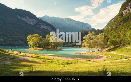 Lago di Tenno (Italien, Alpen) - schöne Landschaft mit Bergsee (mit Insel), Strand und Graswiese, Bergen und blauem Himmel Stockfoto