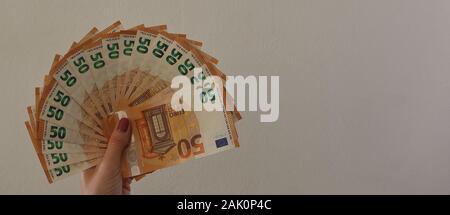 50 Euro-Banknoten in Frauen-Hand, gestrichene Nägel, Nahaufnahme, isoliert auf hellgrauem Hintergrund, Nahaufnahme, Begriff des Vermögens, des Ertragssagens, der Ausgaben, . Stockfoto