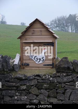 Ehrlichkeit Stall oder Ehrlichkeit, Verkauf Bauernhof Eier von freilaufenden Hühnern eine unbesetzte Holz Stall mit Henne auf einer trockenen Steinmauer in der Derbyshire Peak District Stockfoto